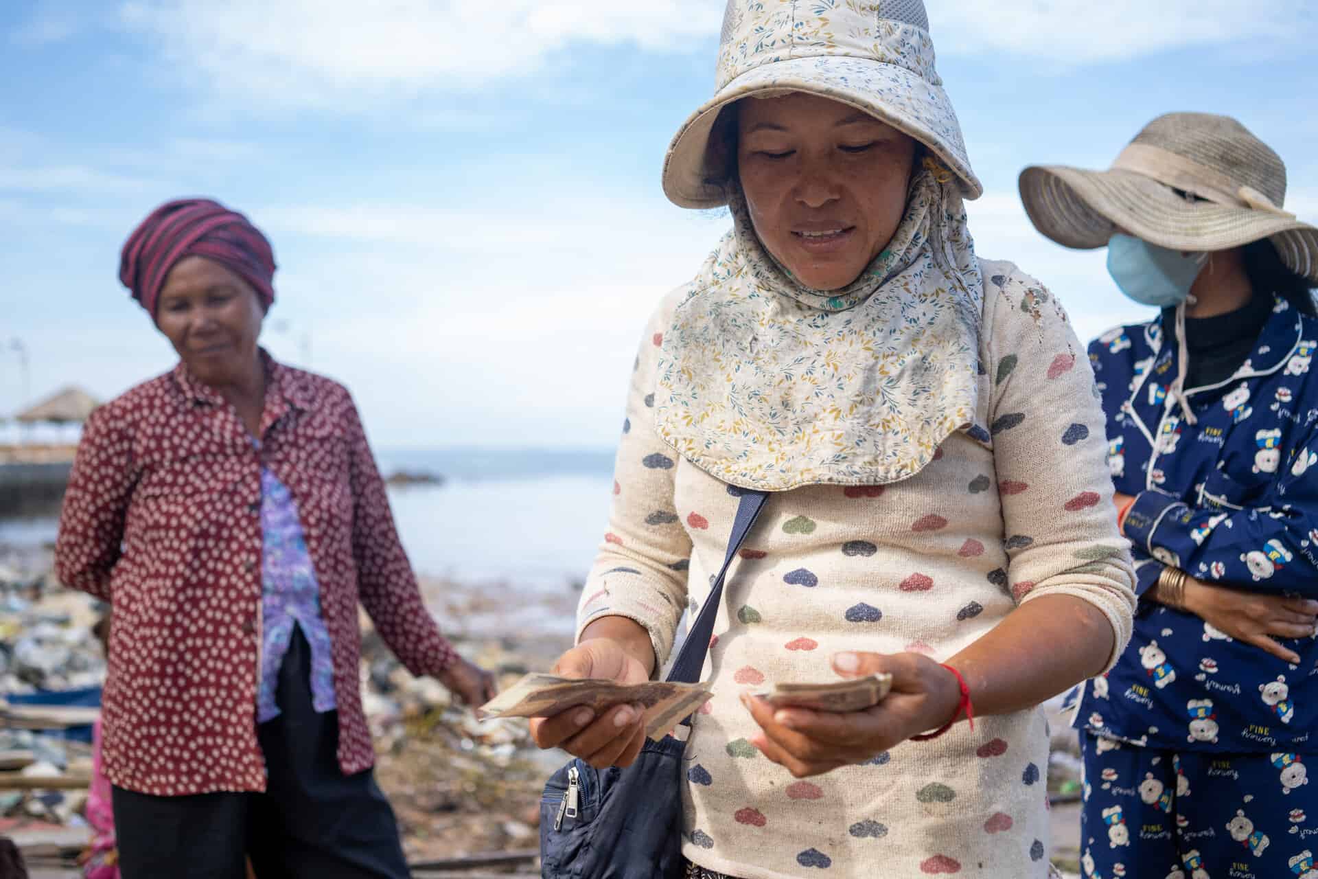 Journée de la Terre 2023 : Deux sœurs achètent des crabes et du poisson aux pêcheurs avant d’aller les vendre au marché, plage d’Angkoal, Cambodge