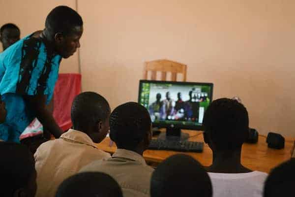 Un enseignant africain donne des cours d'informatique devant un ordinateur à plusieurs élèves