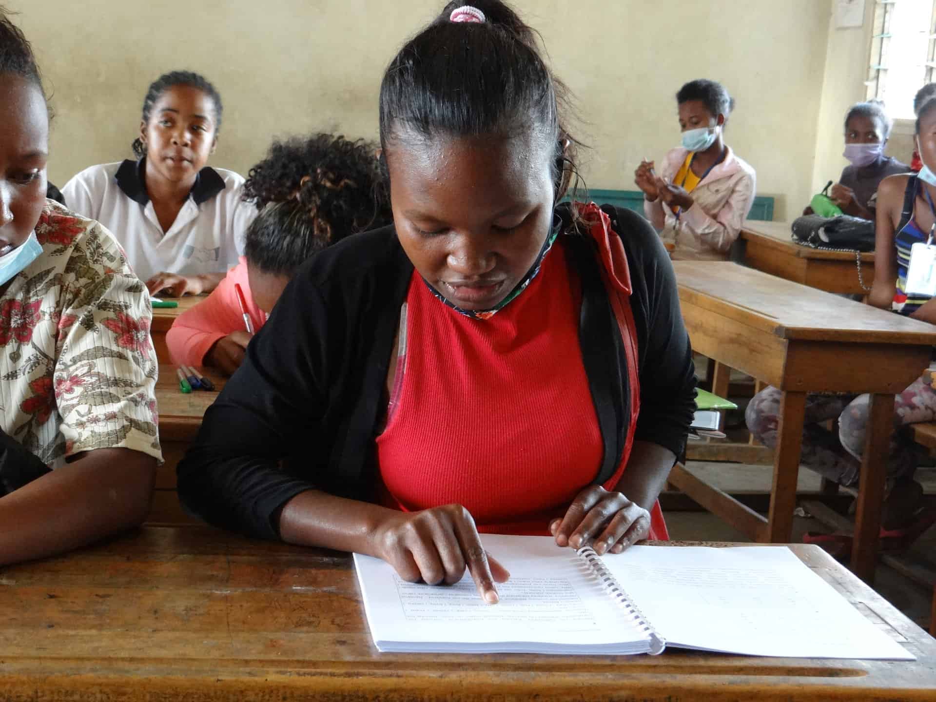 Jeune femme qui lit dans une salle de classe à Madagascar