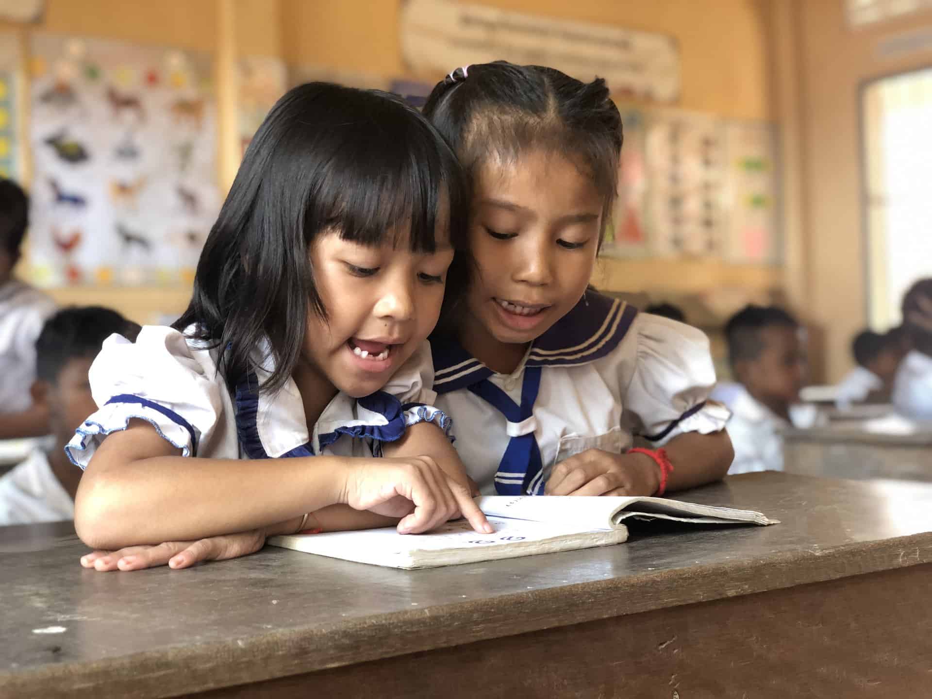 Deux petites filles dans une salle de classe dans le cadre du projet “Consortium cambodgien pour les enfants non scolarisés” (CCOSC). Cambodge, 2023. © Prasith Chin