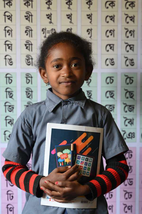 2025-03-INDIA Young girl in India holding her school report book<br />